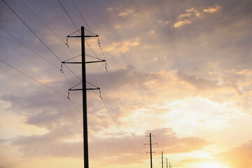Telephone poles and wires against blue sky with clouds