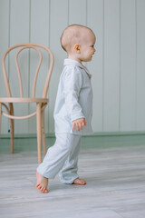Naklejka premium small child of European appearance, a boy with blue eyes in pajamas, walks around the room Children's room for children