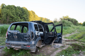 Broken car, abandoned on the road. The stolen car. The wheels have been removed from the car, everything is broken and bent. Getting rid of the stolen car