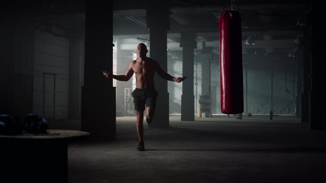 Man jumping with skipping rope in gym. Sportsman doing cardio exercising
