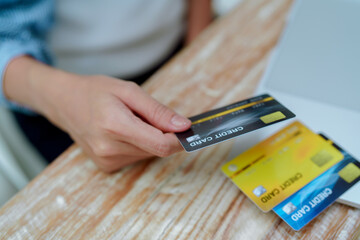 Close Up Credit card in the hand of a young woman near the computer.