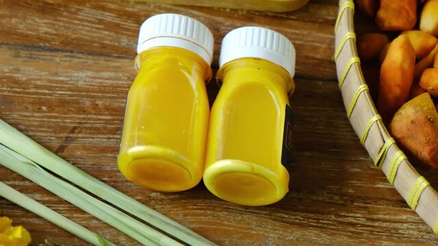 Healthy Jamu drink- Indonesian herbal beverage in glass bottle with natural ingredients: turmeric, ginger, lime, palm sugar, lemongrass, tamarind on wooden table. Healthy lifestyle