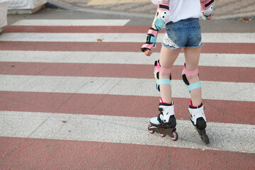 Fototapeta na wymiar Cropped rear view shot of unrecognizable child skating on crosswalk on rollerblades, copy space