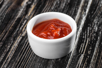 red sauce in a gravy boat on a dark wooden background. barbecue sauce. High quality photo