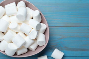 Delicious puffy marshmallows on light blue wooden table, flat lay. Space for text