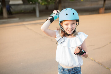 Fototapeta na wymiar Happy young girl knocking on sports helmet she is wearing outdoors, copy space