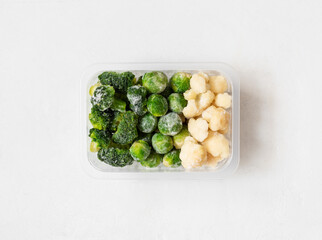 Frozen vegetables. Cabbage set. Broccoli, brussels sprouts and cauliflower in a container on a white background. Top view, flat lay.