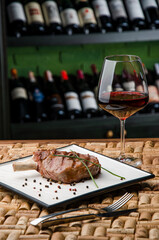 Juicy steak or Rack of lamb and glass of red wine on the background in wine bottle racks. High quality photo