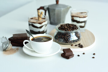 cup of black coffee and coffee beans, dessert in a glass. Cheesecake with chocolate and cottage cheese cream