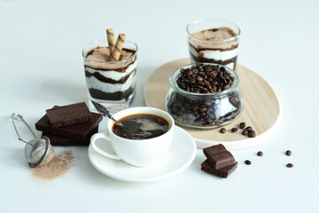 cup of black coffee and coffee beans, dessert in a glass. Cheesecake with chocolate and cottage cheese cream