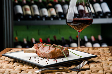 Juicy steak or Rack of lamb and glass of red wine on the background in wine bottle racks. High...
