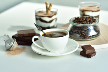 cup of black coffee and coffee beans, dessert in a glass. Cheesecake with chocolate and cottage cheese cream
