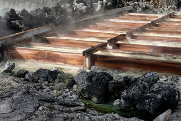 Close up view of yubatake hot spring mist and steam covered wooden track with mineral water in winter,Kusatsu ,Gunma Japan.