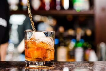 Whiskey is poured into glass. Glass of whiskey on bar counter in restaurant. High quality photo