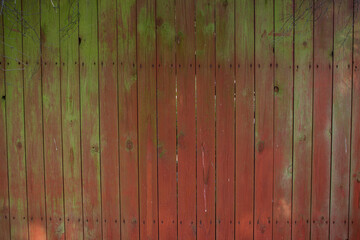 Close up of scratched red and green wooden texture of a fence. Red and green wooden planks