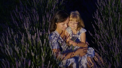 Happy young mother and little girl daughter kid kissing and laughing in aromatic flowers lavender field garden on summer night sunset. Family, childhood, motherhood, fairytale, provence style concept - Powered by Adobe