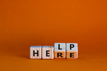 Help is here symbol. Turned wooden cubes and changed the word help to here. Beautiful orange background, copy space. Business, support, motivational and help is here concept.