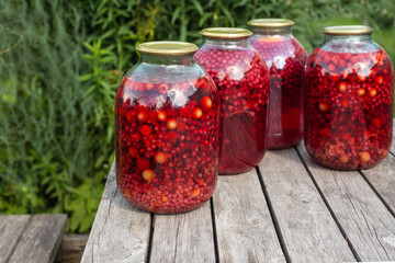 four large jars of compote stand on a wooden table