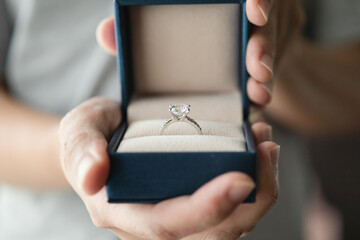 hands holding diamond ring in jewelry box