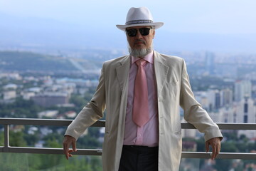 old man in a white hat on the background of the city of Almaty