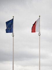 Real world photo of Polish and European Union flags. Polish and EU flag on pole. Government relationship concept.