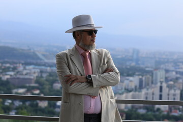 old man in a white hat on the background of the city of Almaty