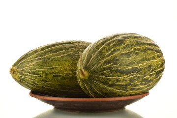 Two juicy ripe melons on a clay dish, close-up, isolated on white.