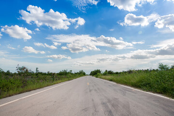 Fototapeta na wymiar Driving on an empty road. Empty asphalt road through the green field and clouds on blue sky in summer day. Open road ahead, endless road for concept.