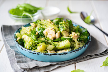 Diet lunch: salad with broccoli, chicken and vegetables on a beautiful plate on a white table.