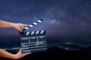 Man hands holding movie clapper on Milky Way , Stars and mountains. Shown slate board. use the...