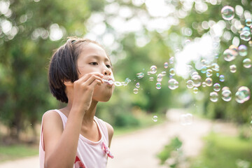 girl playing with blowing bubbles in the park.