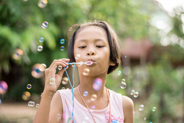 girl playing with blowing bubbles in the park.