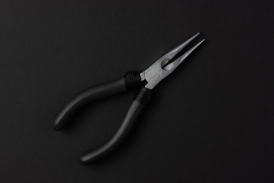 Isolated metal pliers with plastic black handles