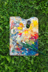 Real Artist's palette with multiple colors on the green  grass. Oil paints of different colors