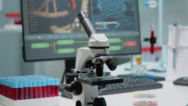 Close up of chemical microscope and medical research equipment in scientific laboratory. Liquid examination tool with glass lens and blood samples in vacutainers on professional desk