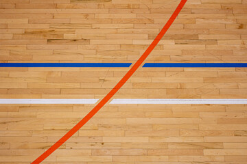 The worn wooden floor of the sports basketball hall with colorful marking lines.