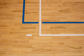 The worn wooden floor of the sports basketball hall with colorful marking lines.