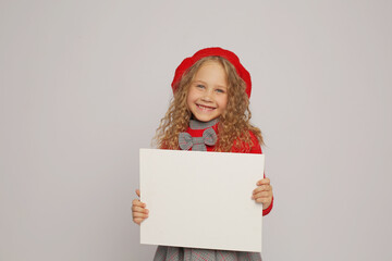 a beautiful blonde girl in a red jumper sweater and a red beret holds a white sheet of paper