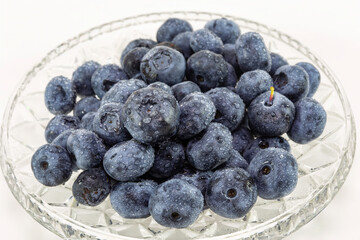 Juicy sweet blueberries in a plate on a white background