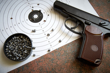 A sports pistol on the background of a target with bullet holes and lead bullets.