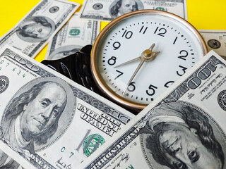 Watch and assorted American banknotes. Time is money idea