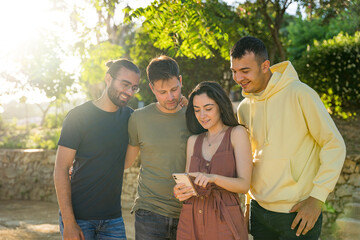 Friends smiling while looking at a mobile phone. They are together looking at the same mobile phone.They are wearing colourful clothes. She is using the mobile phone. Caucasian. Javea, Alicante.