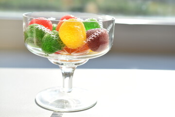 Marmalade in sugar in a glass vase on a white background
