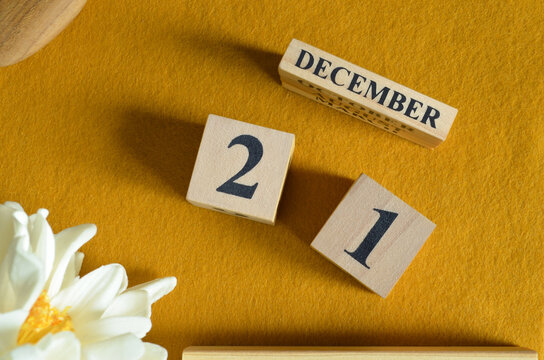 December 21, Wooden Calendar cube on yellow felt fabric with peony flower for date icon background.
