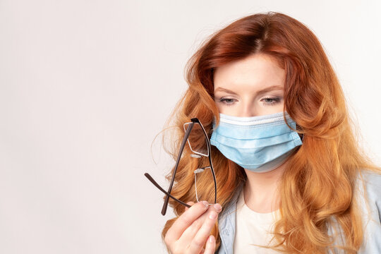 Woman Examines Her Glasses That Fog Up When Wearing A Medical Mask