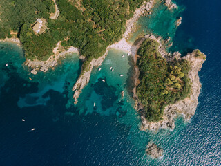 Aerial view of Corfu island. White boats float in turquoise water near the shore. Heart shaped...