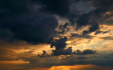 beautiful sunset sky, bright sun and dark silhouette of clouds as a background