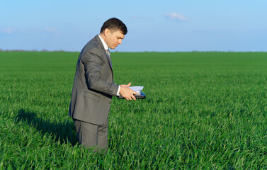 businessman works in a green field, freelance and business concept, green grass and blue sky as background