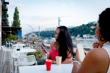young sisters having a drink and using their smartphone in the city of lyon france