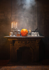 Scary laughing pumpkin and old skull on ancient gothic fireplace. Halloween, witchcraft and magic.